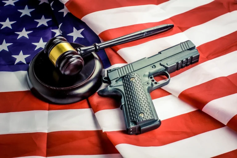 Handgun and judge gavel on American flag symbolizing U.S. gun law and justice