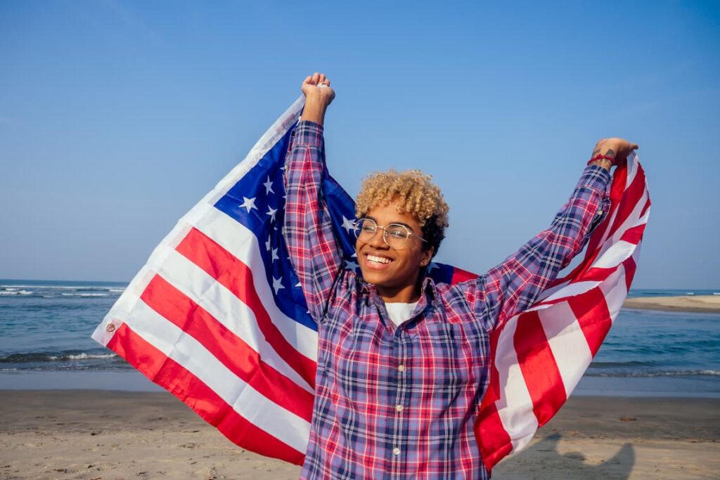 Smiling person with American flag celebrating restoring rights on the beach