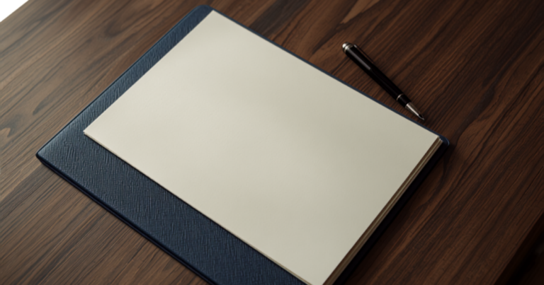 Blank paper stack and a pen on a navy portfolio on a wood desk